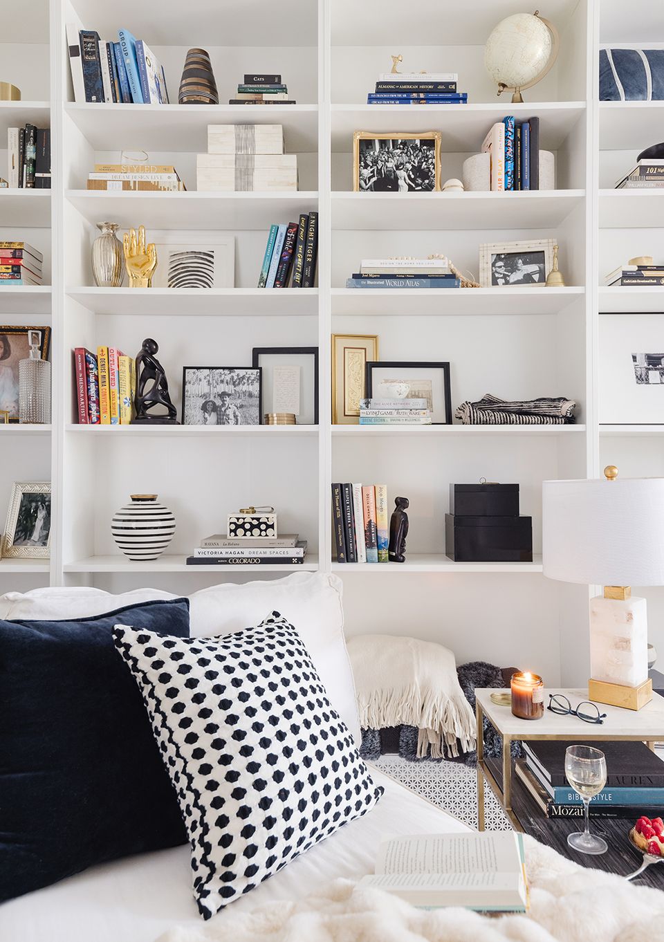 Modern minimalist shelving corner with navy and white color palette, geometric patterned pillows, and curated book and decor display