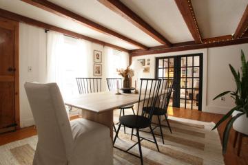 Polished farmhouse dining room blending dark wood beams, light table, and elegant black spindle chairs