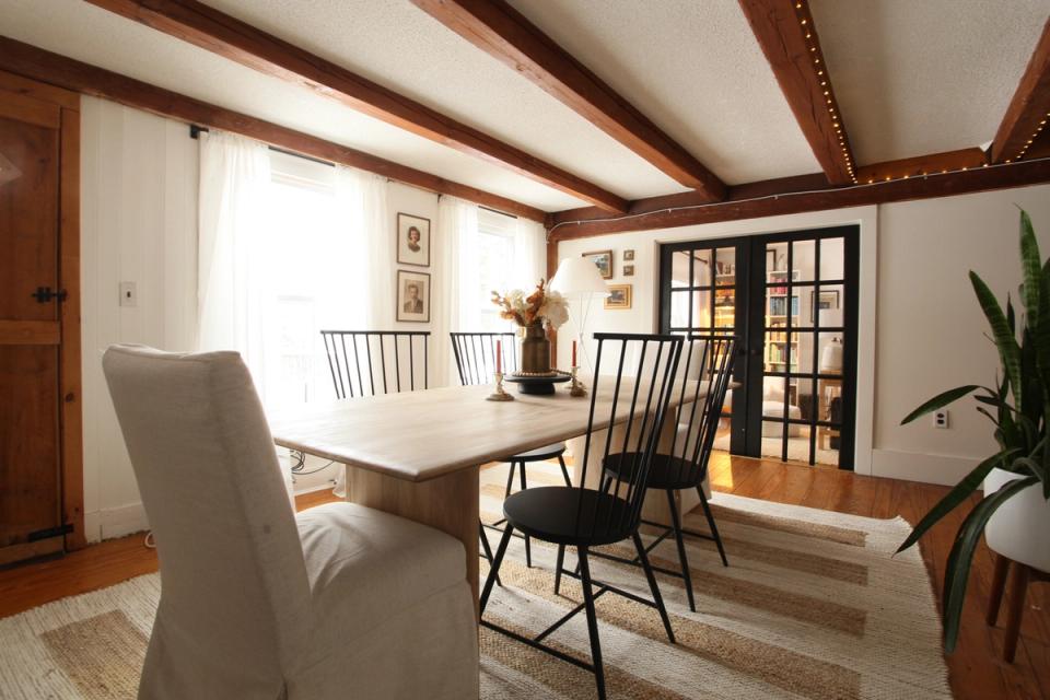 Polished farmhouse dining room blending dark wood beams, light table, and elegant black spindle chairs