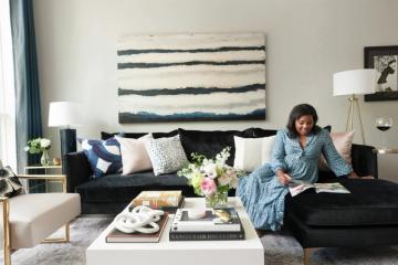 Modern living room with black sectional, neutral palette, and striped abstract wall art creating a sophisticated, budget-friendly luxury aesthetic