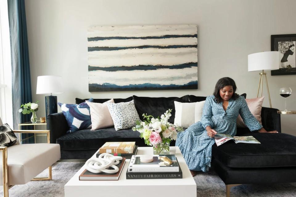 Modern living room with black sectional, neutral palette, and striped abstract wall art creating a sophisticated, budget-friendly luxury aesthetic