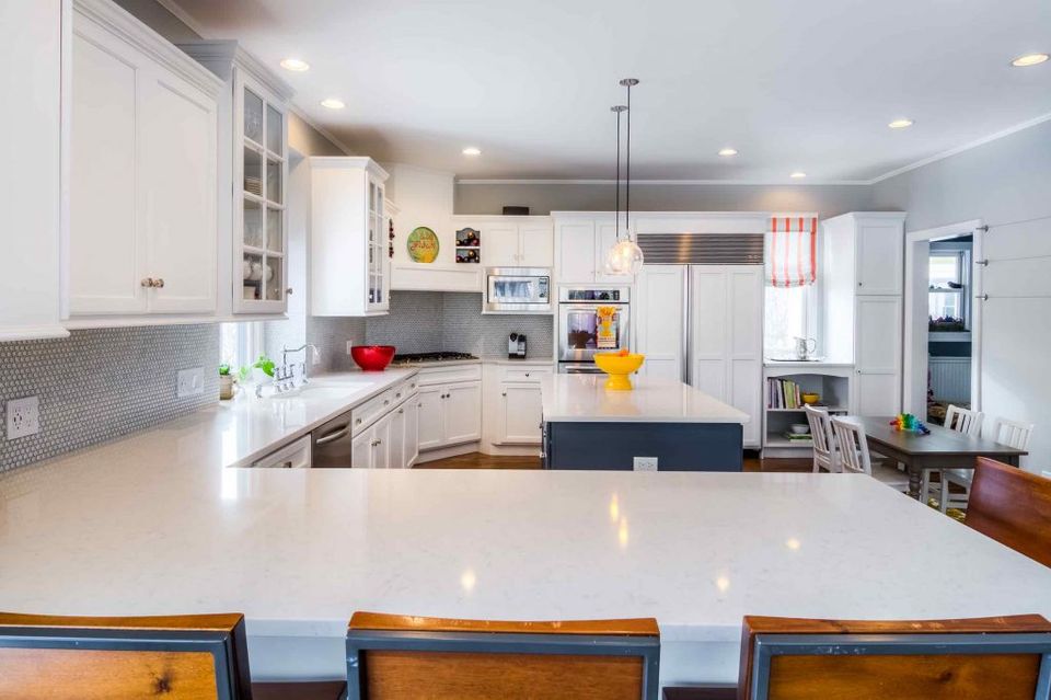 Bright, clean modern kitchen with white cabinetry, stainless steel appliances, and spacious white quartz island