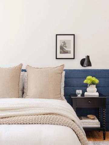 Contemporary bedroom blending navy headboard with neutral palette and minimalist wall art