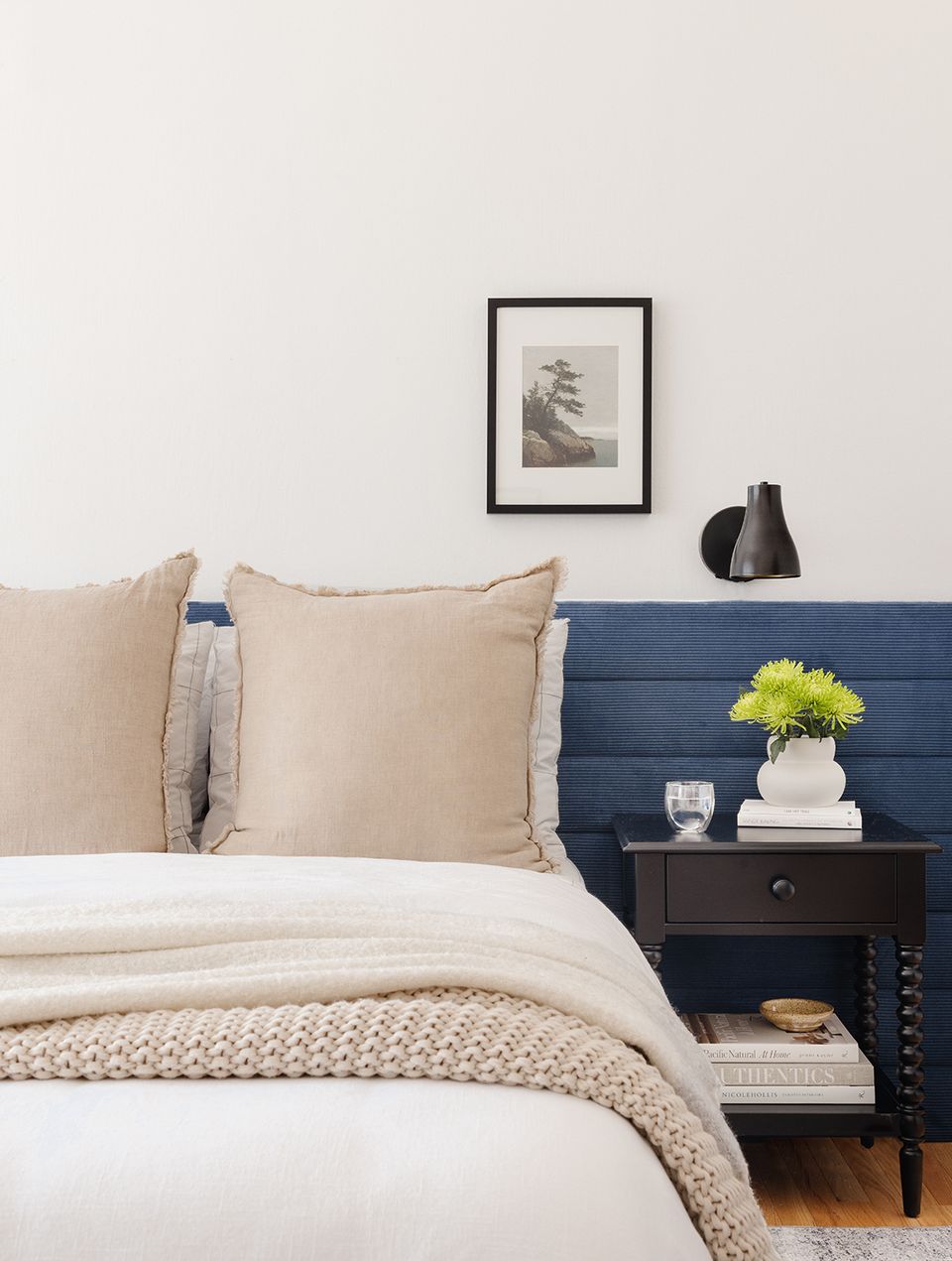 Contemporary bedroom blending navy headboard with neutral palette and minimalist wall art