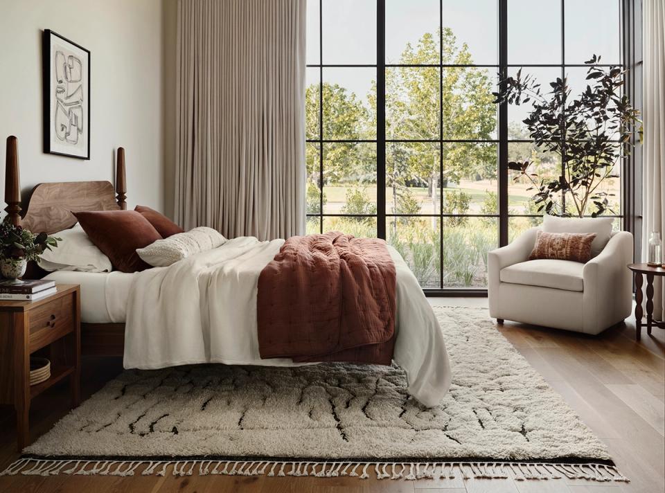Bohemian bedroom with warm terracotta accents, layered textures, and natural light from large windows