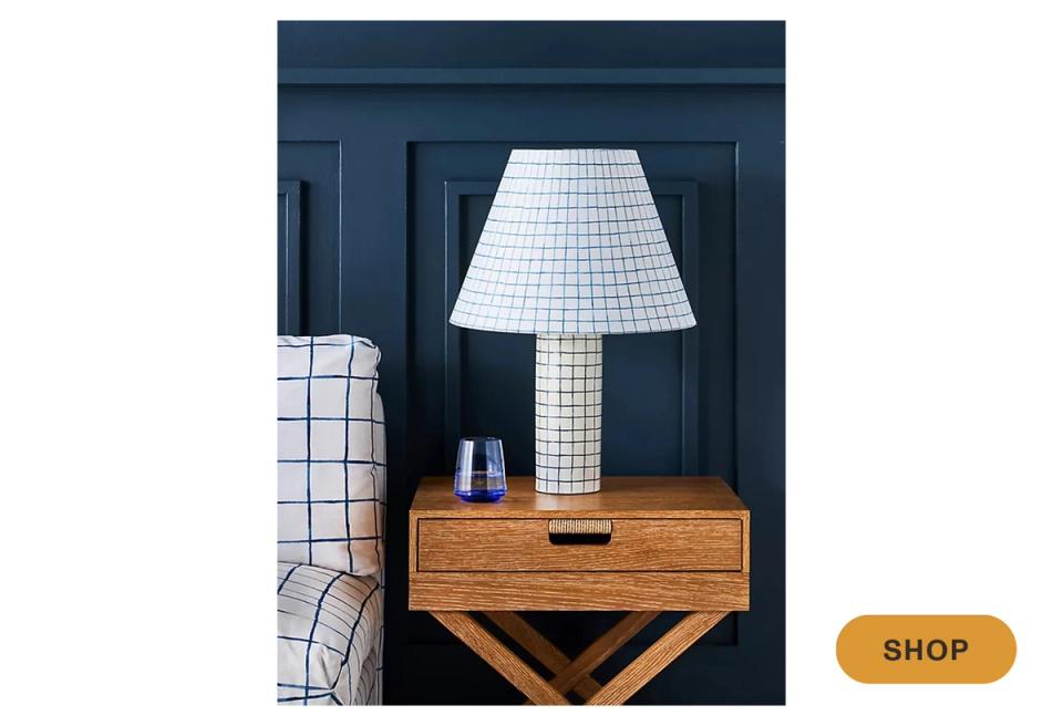Dark blue modern interior with white grid lamp and warm wood nightstand