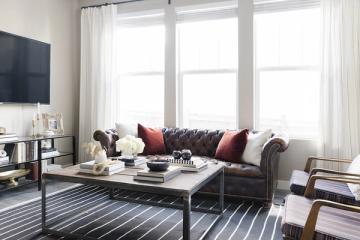 Bright farmhouse living room with exposed brick wall, gray modular TV stand, and warm neutral tones