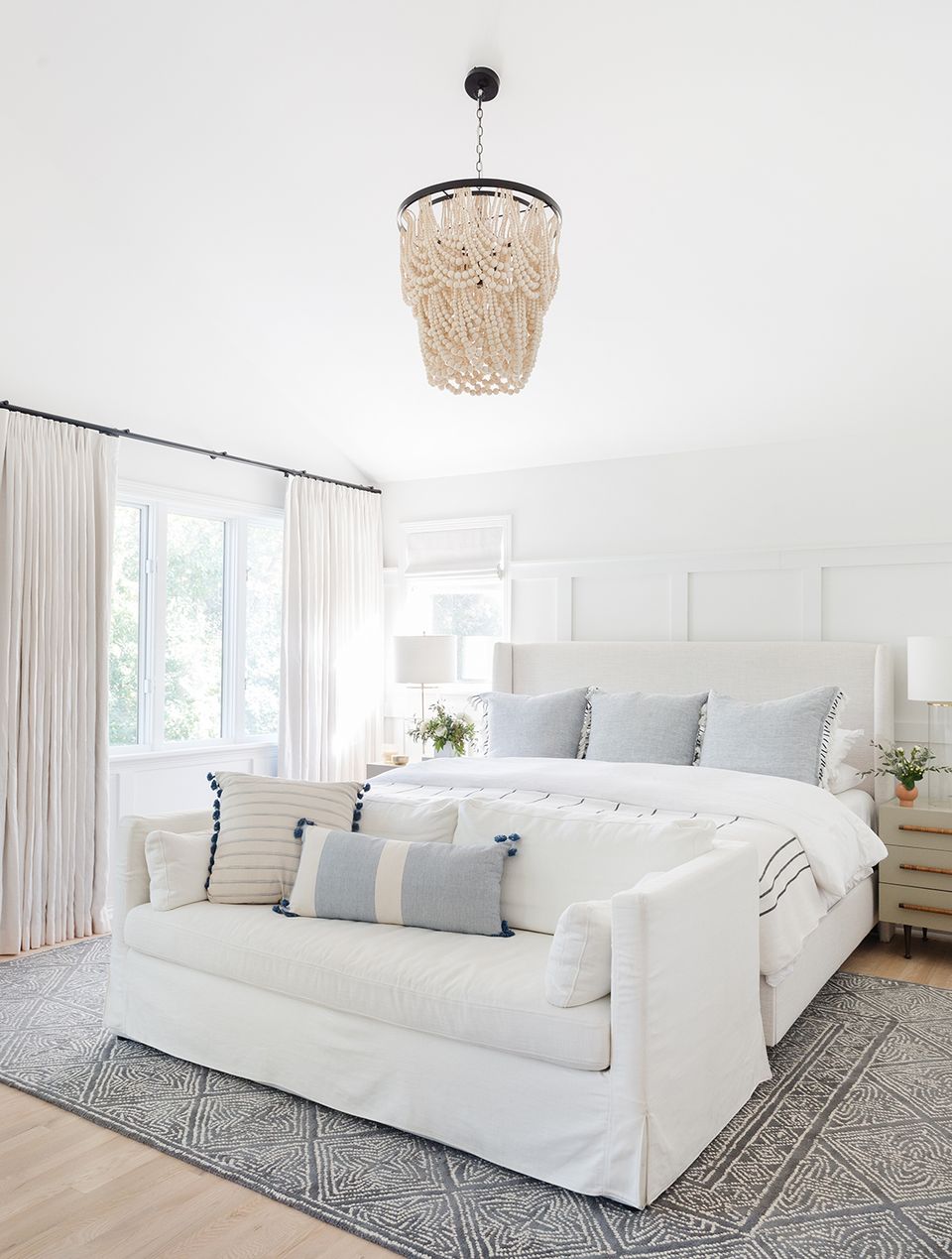 Coastal bedroom with woven rattan pendant and crisp white bedding