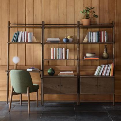 Home office with a wall-mounted wood shelving unit, a green desk chair, and a task lamp