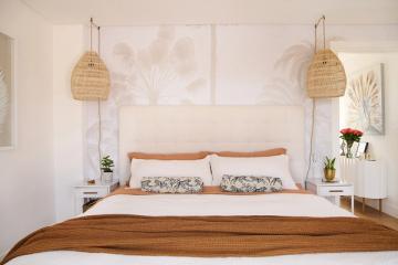 Coastal-inspired bedroom with natural wood accents, rattan pendants, and soft neutral tones