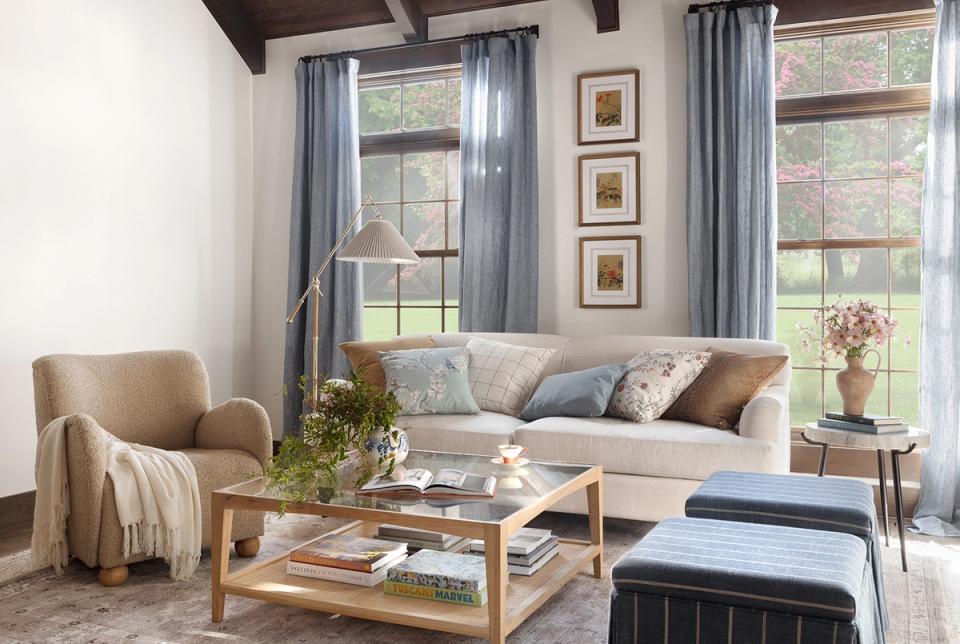 Calm living room mixing natural wood, warm neutrals, blue accents, and layered window treatments