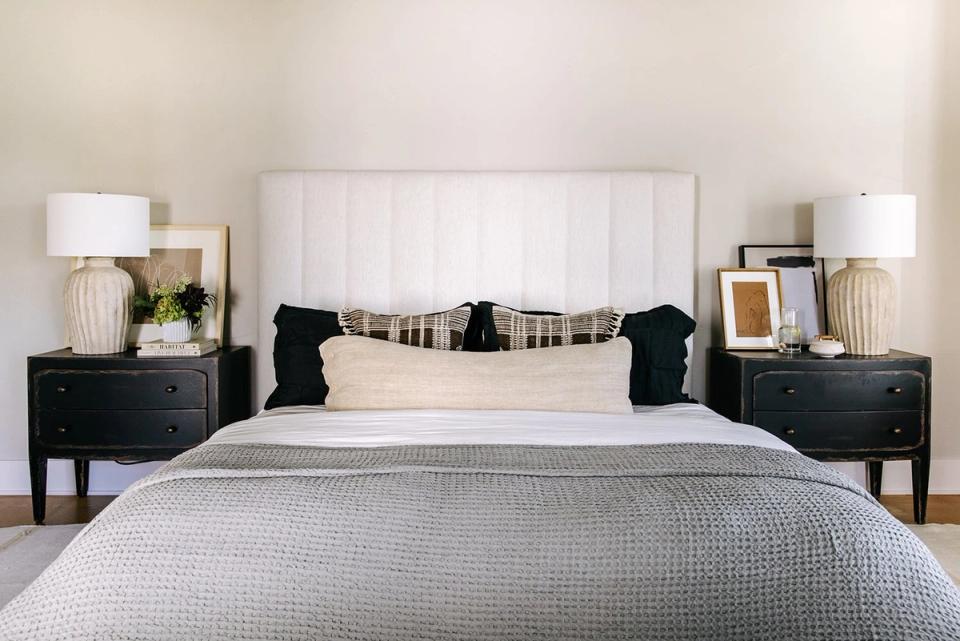 Contemporary bedroom in soft neutrals with white headboard, black nightstands, and layered textures creating restful balance.