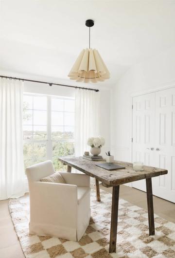 Bright, airy office space with rustic wood desk, cream armchair, and natural pendant lighting