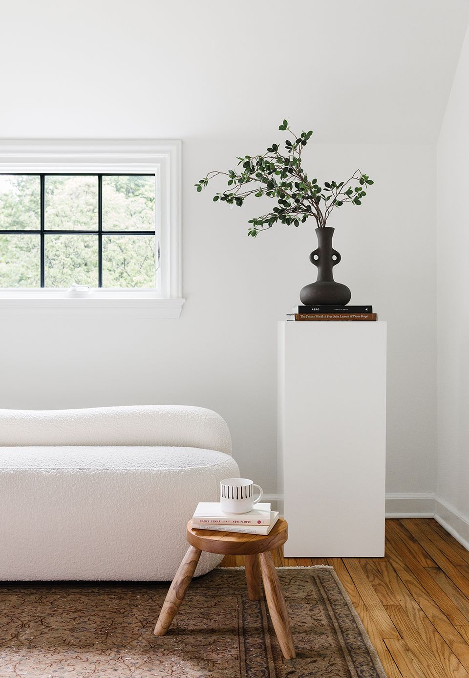 Calm bedroom corner with cream upholstered bed, wooden side table, and black sculptural vase