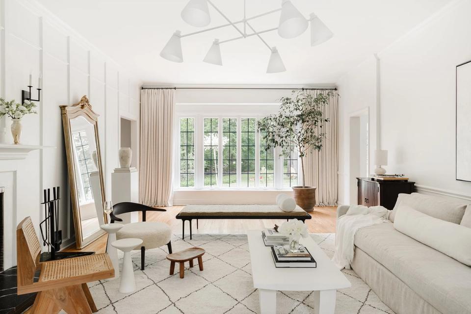 Bright minimalist living room with cream palette, geometric rug, and natural light from large windows