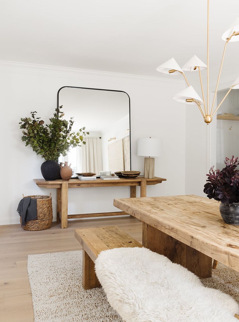 Scandinavian-inspired dining space with natural wood table, cream textiles, and warm brass pendant lighting