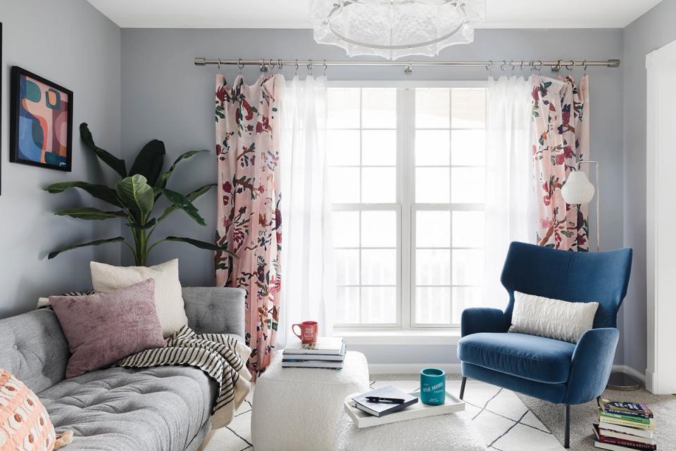 Romantic cottage bedroom-living hybrid with floral curtains, blue chair, and soft pink tones