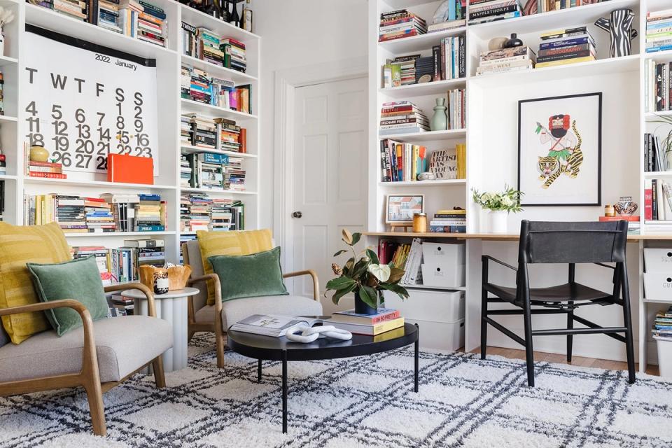 Transitional library featuring floor-to-ceiling shelving, mustard accents, and functional furniture creating visual interest.