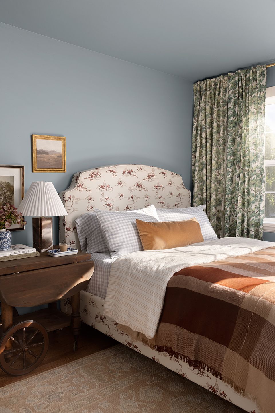 Serene blue-gray bedroom with floral headboard, warm wood tones, and classic elegance