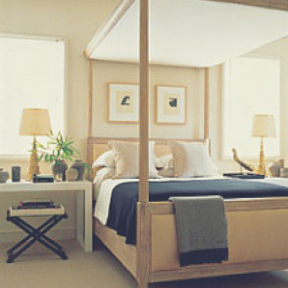 Serene bedroom with natural wood canopy bed, neutral palette, navy accents, and warm ambient lighting