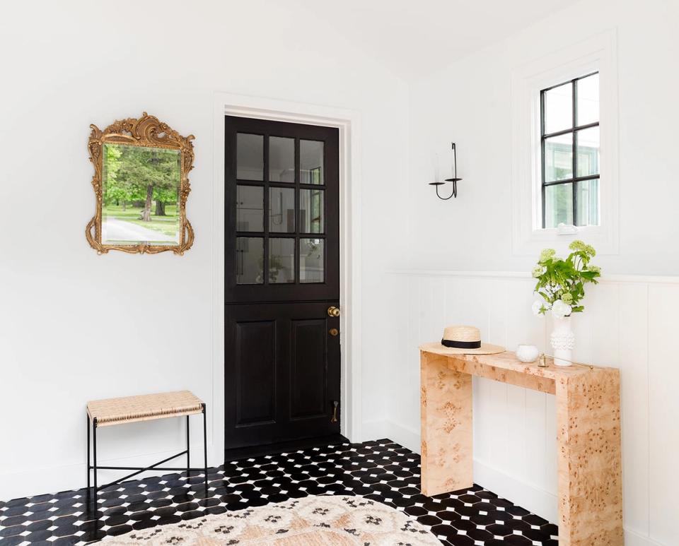 Modern farmhouse entryway with black-and-white tile, natural wood console, and dark door