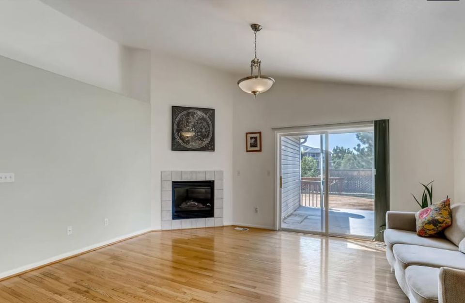 Contemporary open living space with natural wood floors, linear fireplace, clean white walls, and bright natural light