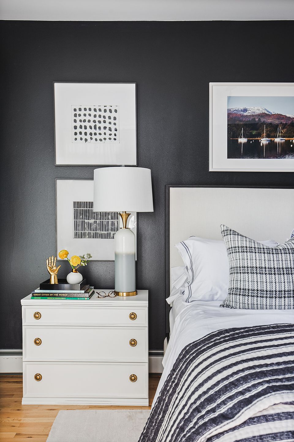 Contemporary bedroom with dark gray walls, navy striped bedding, and brass hardware accents