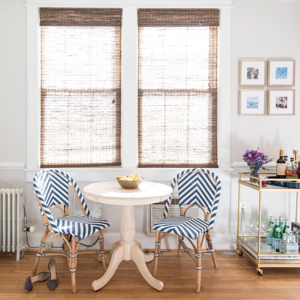 Eclectic coastal dining nook with natural woven roman shades and navy geometric patterned chairs