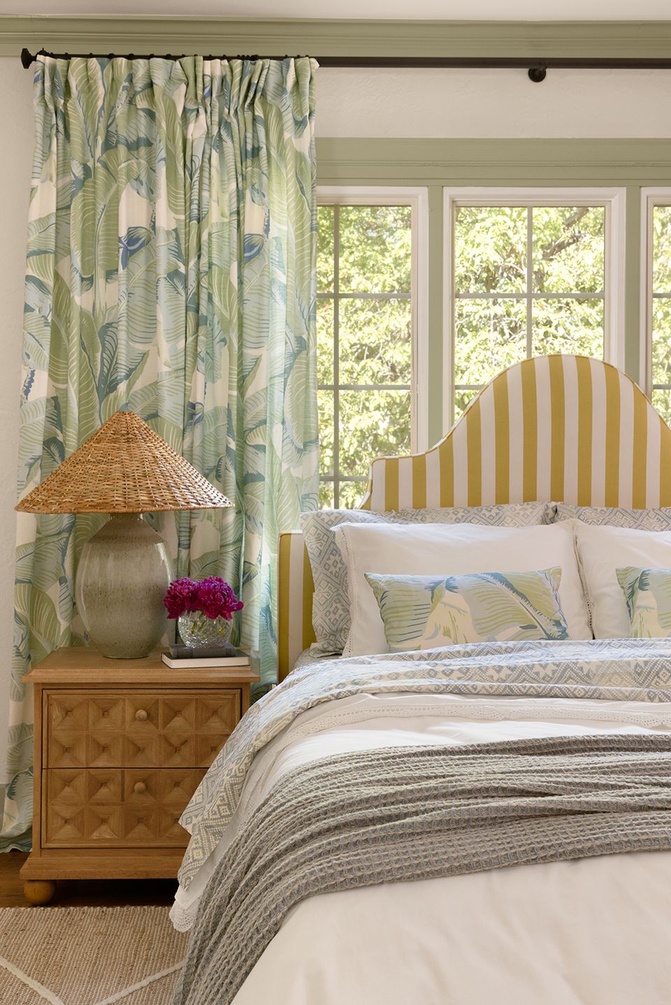 Elegant maximalist bedroom with striped headboard, botanical curtains, and soft green-cream color scheme