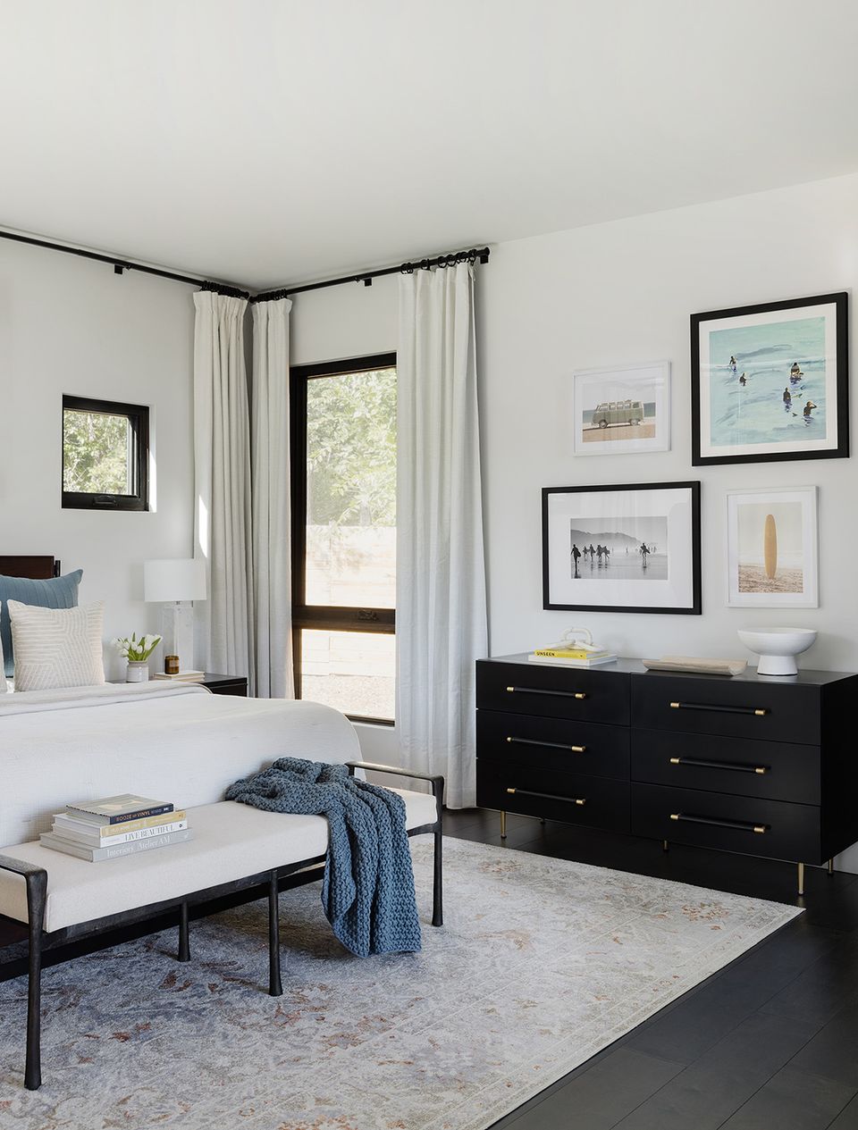 Contemporary bedroom with black dresser, flowing white curtains, and gallery wall arrangement