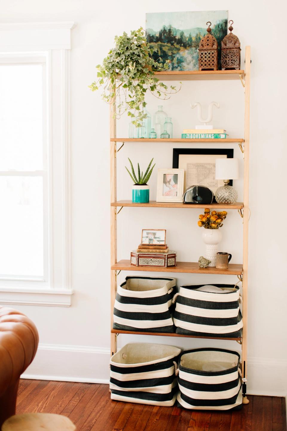Scandinavian shelving system with natural wood, black-striped storage baskets, and curated botanical styling.
