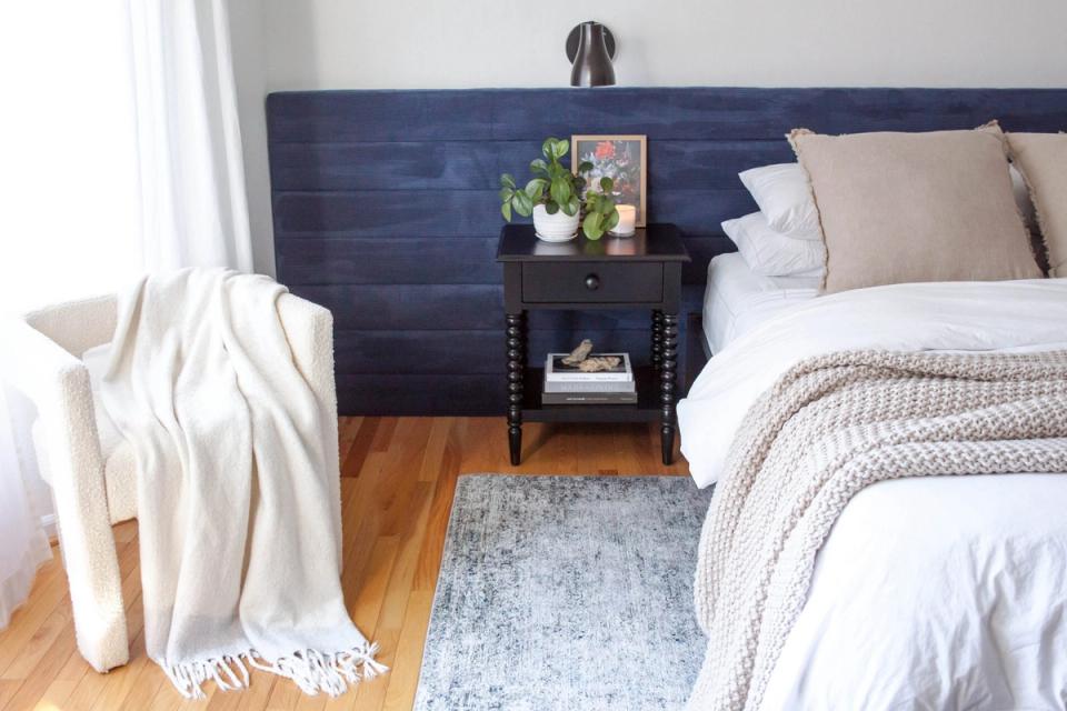 Serene bedroom with navy DIY shiplap headboard, cream bedding, warm wood floors, and soft neutral accents creating a cozy modern farmhouse atmosphere.