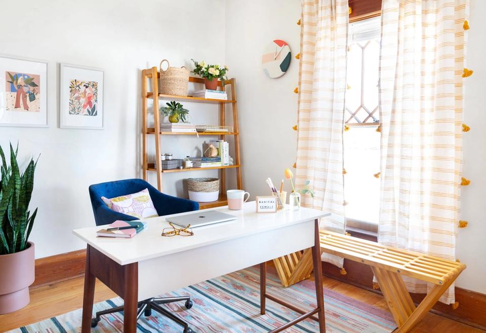 Bright mid-century modern office with warm wood tones, blue accent chair, natural wood shelving, and cheerful checkered curtains