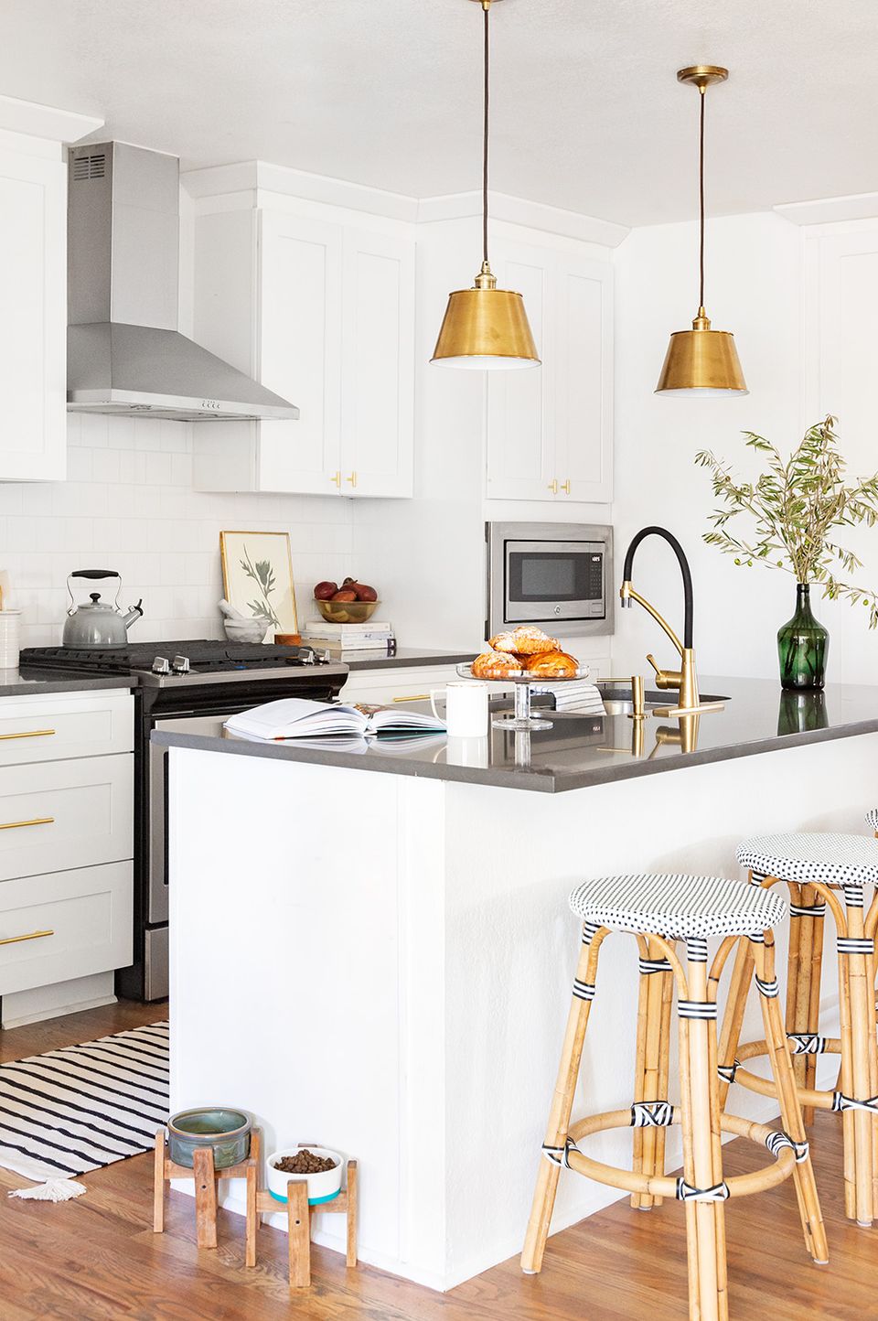 Scandinavian kitchen with white cabinetry, black island, and warm brass pendant lights