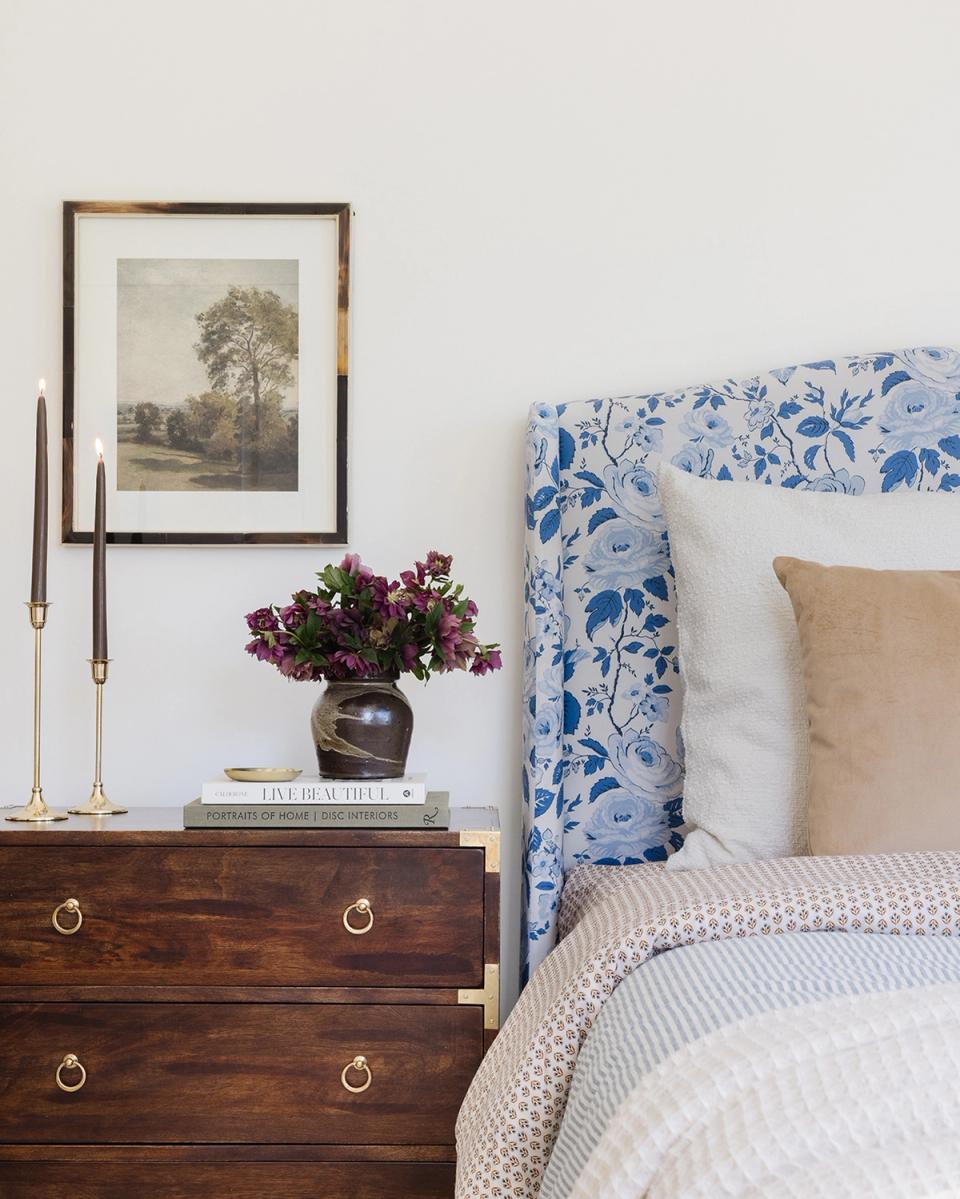 Elegant traditional corner with blue floral headboard, wood nightstand, and botanical art