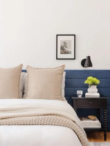 Calm bedroom with neutral tones, navy wood-paneled nightstand, and lime green accent flower arrangement