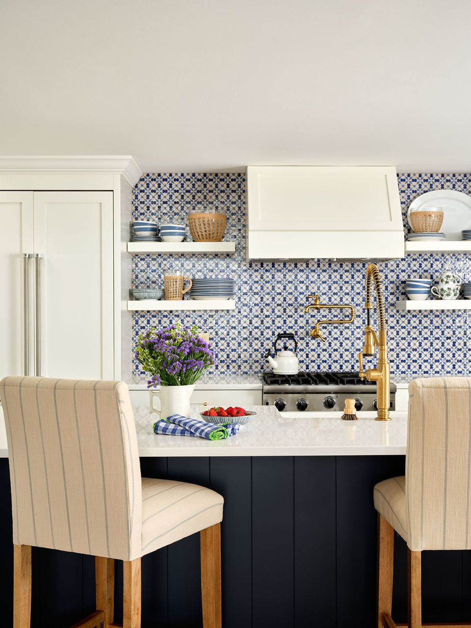 Eclectic galley kitchen with geometric blue tile backsplash, open shelving, and cream upholstered seating