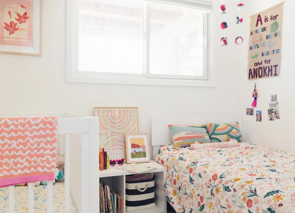 Maximalist girl's bedroom with coral geometric patterns, gallery wall, and cheerful floral bedding