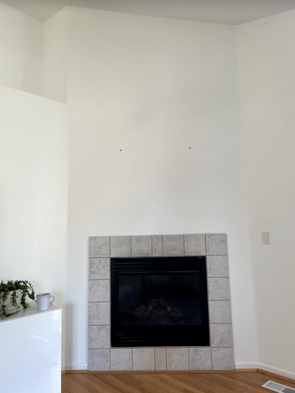 Clean, minimal fireplace surround with light gray tile and bright white walls, modern simplicity