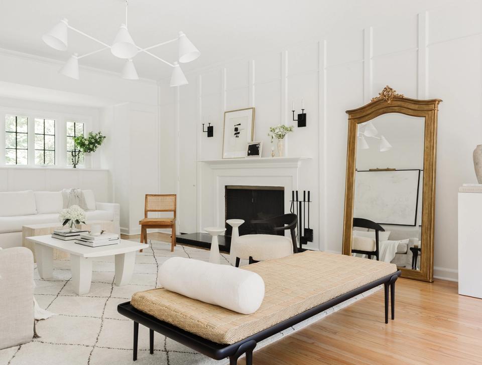 Serene minimalist living room with white walls, natural wood accents, and black pendant lighting