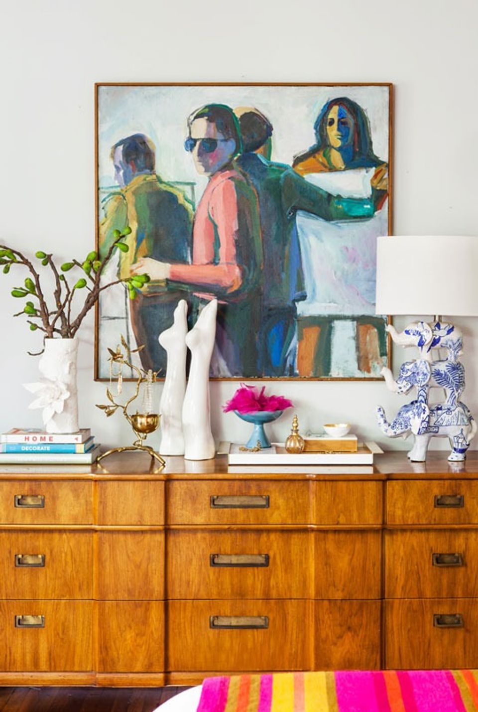 Mid-century modern dresser styled with vibrant art, brass accents, and bold pink pop