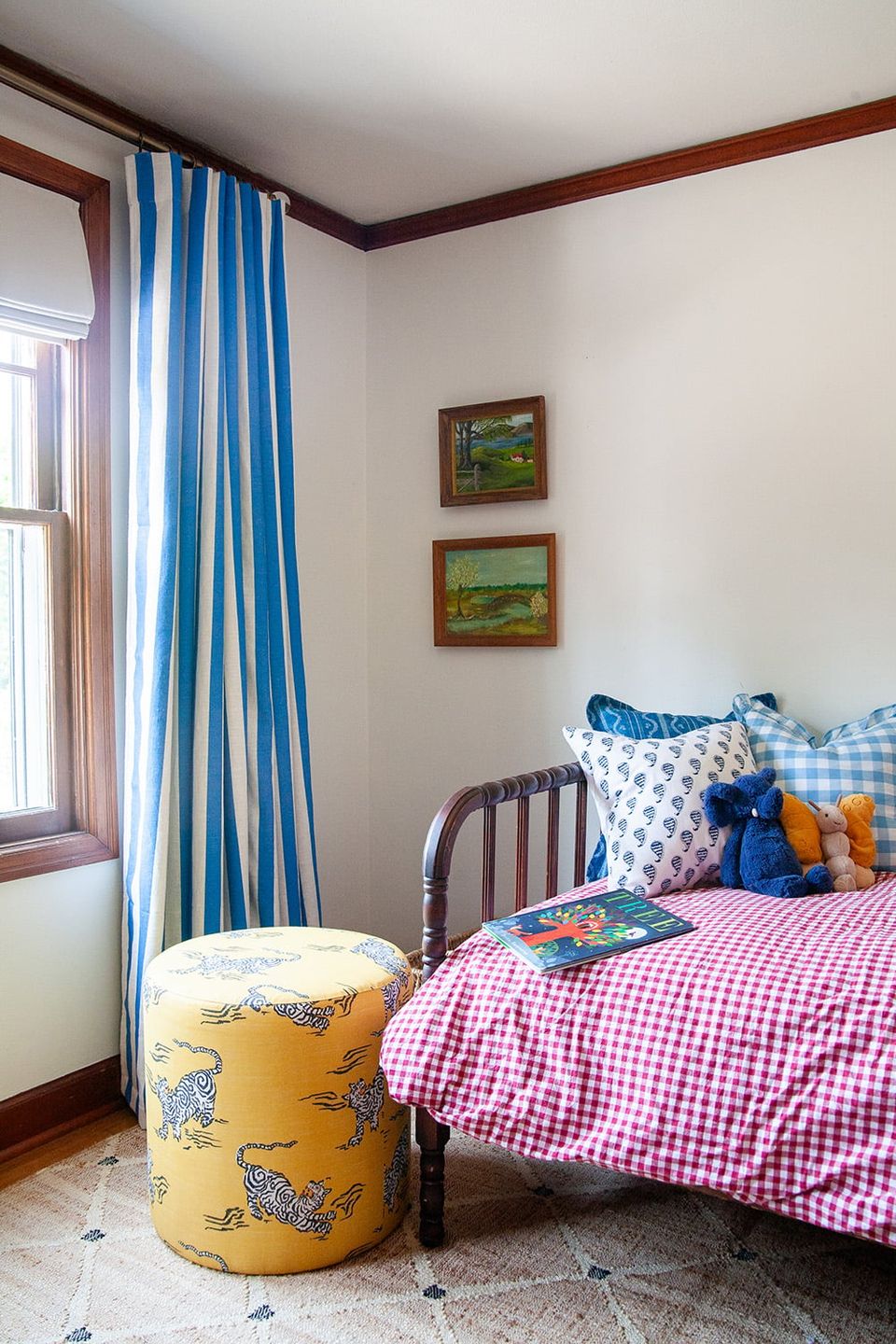 Preppy boys bedroom with nautical blue striped curtains, pink gingham bedding, and traditional wood furniture creating a classic, cheerful atmosphere.
