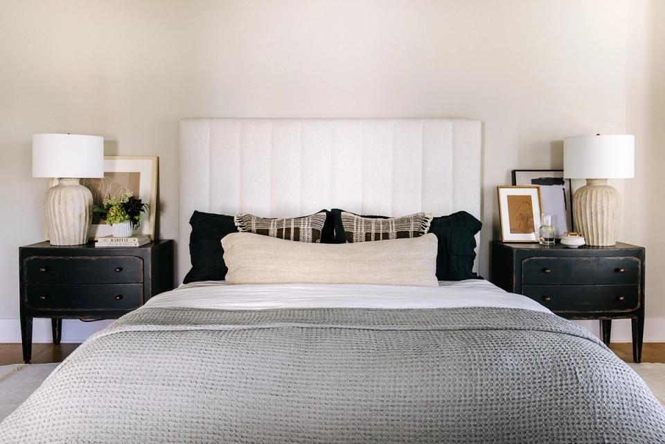 Classic transitional bedroom with black nightstands, white headboard, and neutral textured layers