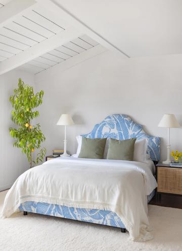 Serene minimalist bedroom with blue patterned headboard, white linens, and potted greenery