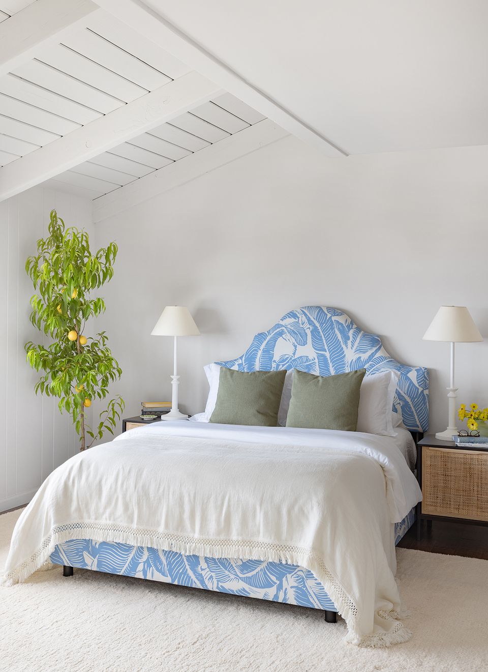 Serene minimalist bedroom with blue patterned headboard, white linens, and potted greenery