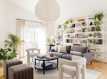 Bright modern living room with beige tones, plants, and open shelving creating an airy, botanical-inspired atmosphere