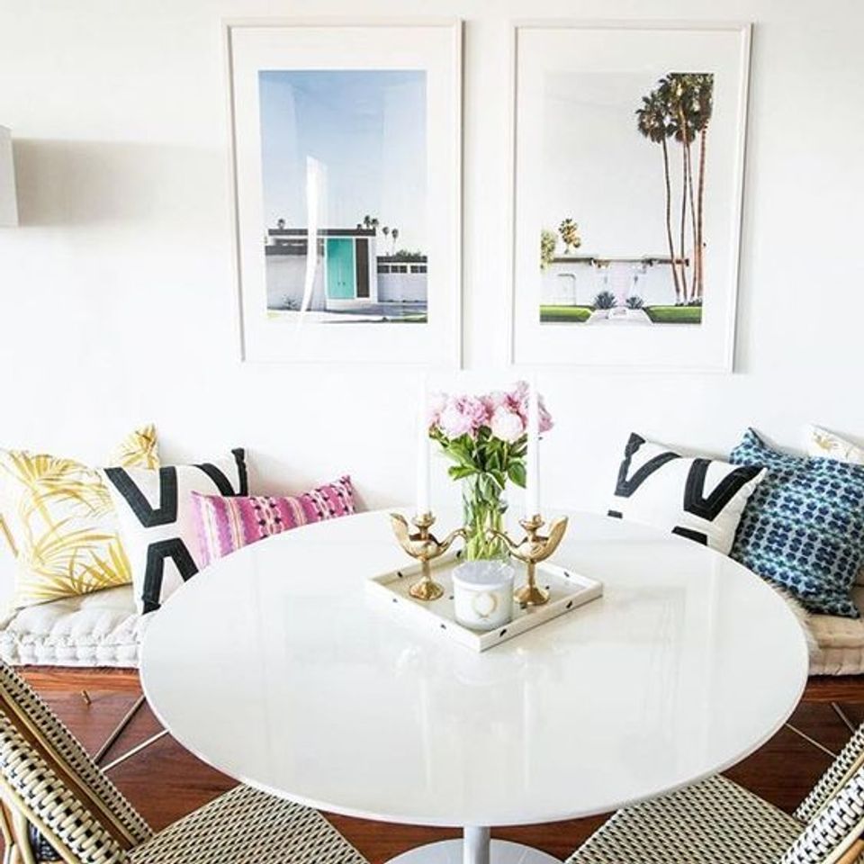 Contemporary living room with bold geometric pillows, white round table, and gallery-style wall art