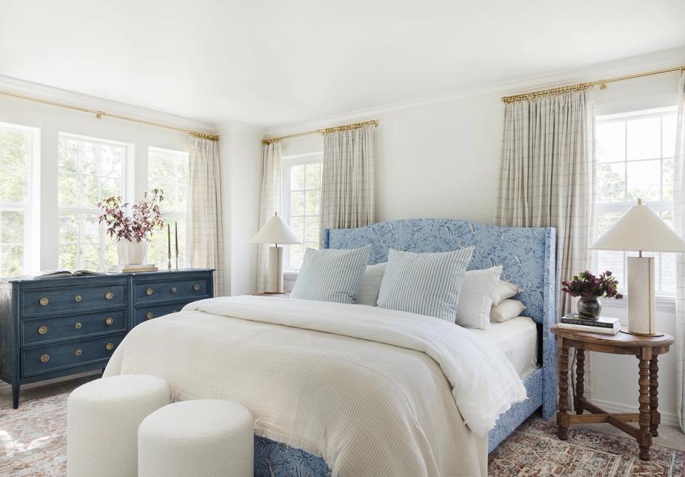 Serene coastal bedroom with blue quilted headboard, cream bedding, and soft neutral palette