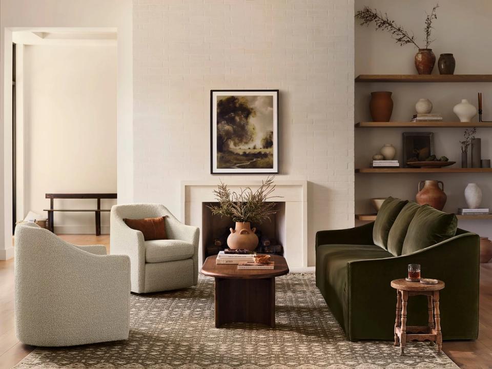 Minimalist organic modern lounge with cream and olive armchairs, white fireplace, terracotta ceramics, and neutral palette