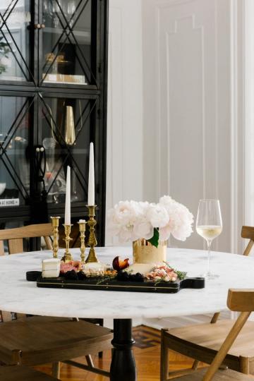 Modern black and white marble dining setup with gold candlesticks, white florals, and contemporary elegance